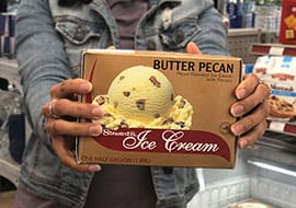 girl holding up half gallon of butter pecan