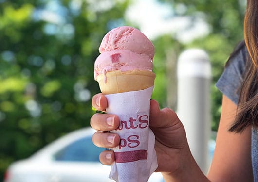 hand holding strawberry ice cream cone