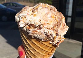 A waffle cone of Peanut Butter Pandemonium, a vanilla ice cream with peanut butter cups, and swirls of chocolate fudge and peanut butter