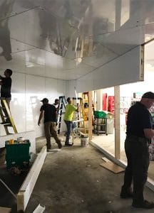 Inside a cooler being built. 5 men working
