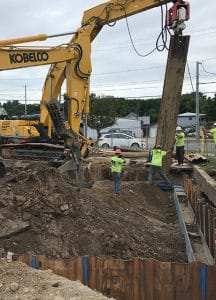 Heavy construction equipment and three men working to lay steel beams