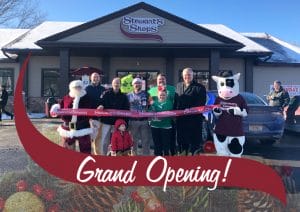 Grand Opening! A group gathered at a ribbon cutting event with a Stewarts shop in the background.