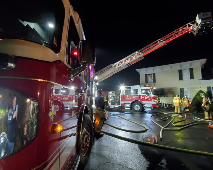 Fire trucks at night. Firefighters in front of a yellow building