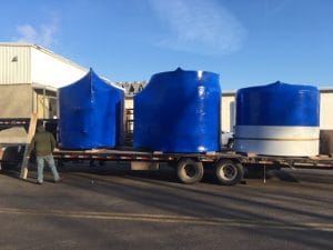 three tanks wrapped in blue plastic on a big truck