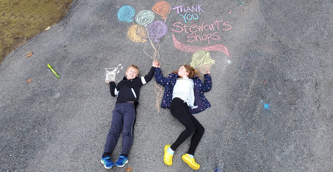 two kids on a driveway with chalk drawings that say thank you stewarts