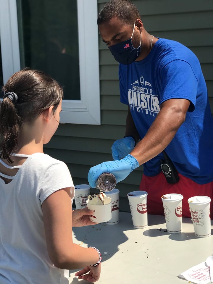 Volunteer scooping ice cream with camper.