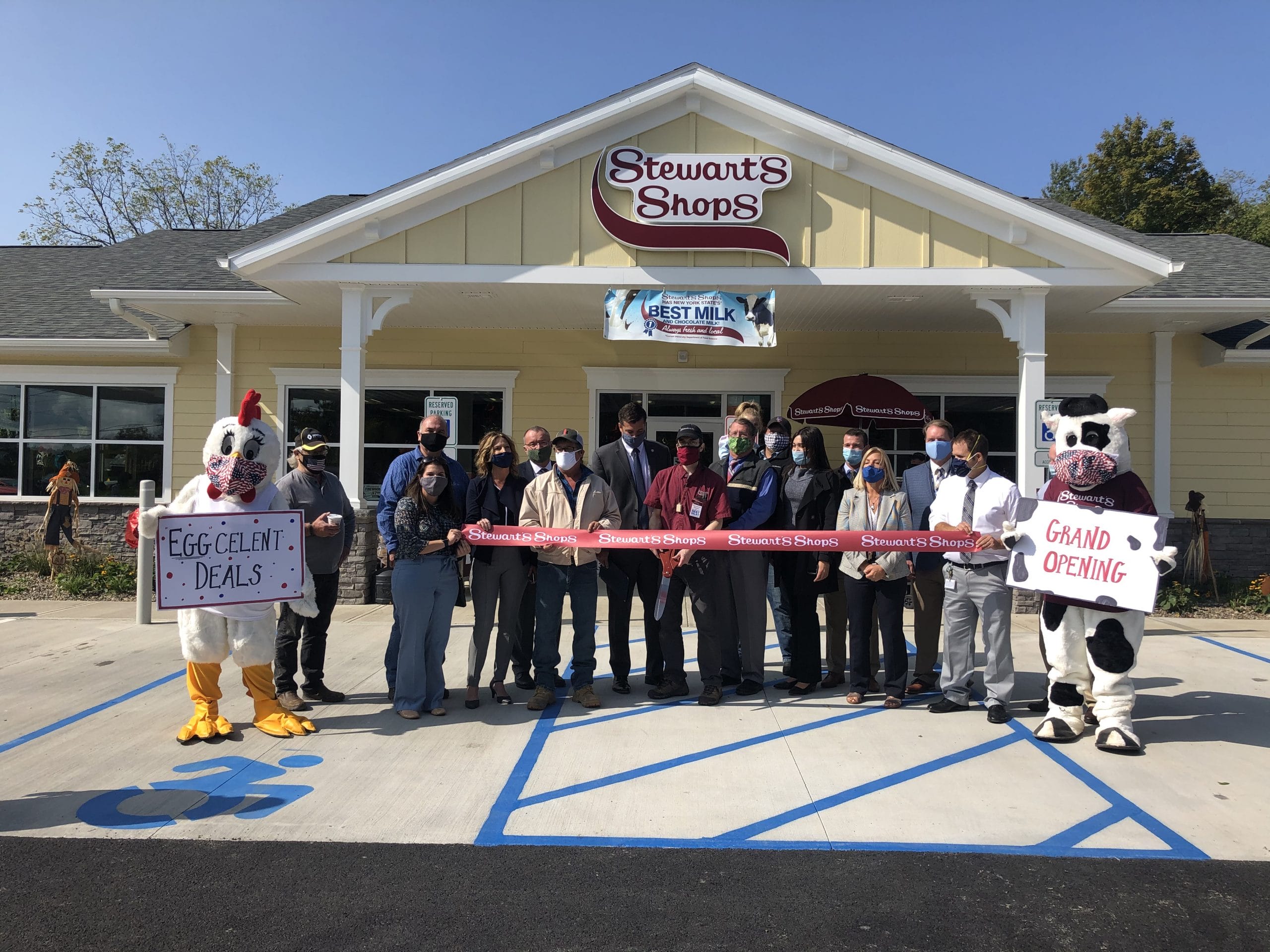 Ribbon cutting at the Shop. Eggcelent deals and grand opening written on signs.