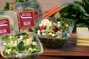 green salads on a cutting board with salad ingredients in the background