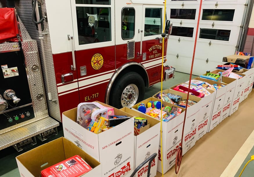 Toys for tots boxes in front of a firetruck.