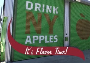 Drink NY Apples It's Flavor Time. A garage door in an urban setting.