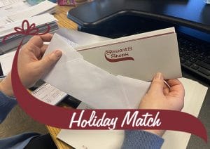Stuffing a holiday match check into an envelope. Holiday Match wave.