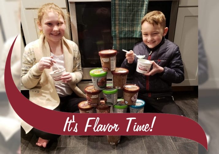 Two kids eating Stewart's ice cream with a pyramid of pints in between them.