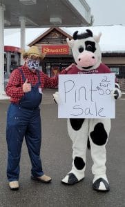 Shop Manager Jason dressed as a cowboy, and Flavor the Cow holding a Pint Sale sign