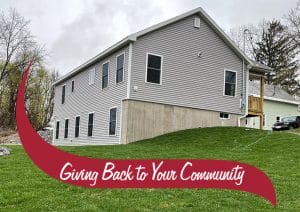 The back of a grey house with a nice green lawn. Giving back to your community.