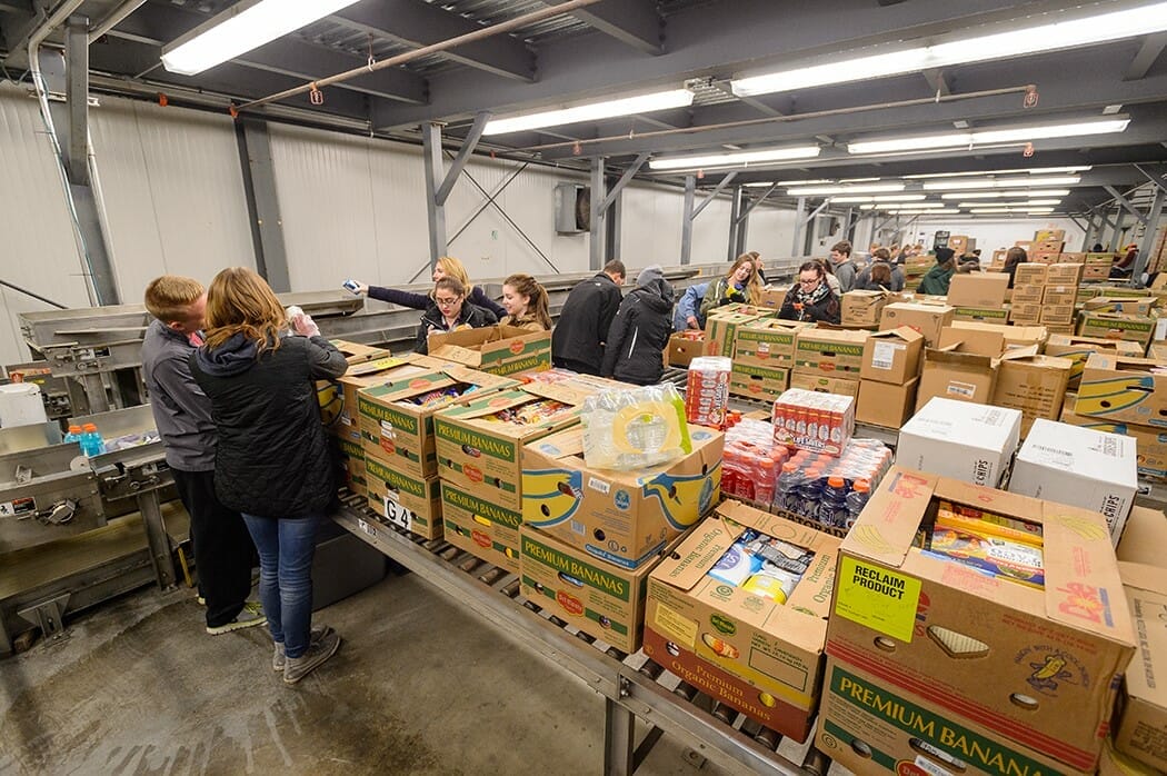 a wide shot of a food pantry with people packing food. 