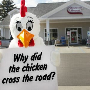 Fresh the chicken (mascot) is holding a sign that reads: Why did the chicken cross the road?"