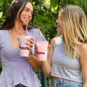two girls holding milkshakes