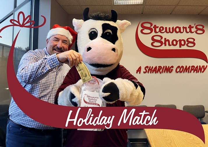 Chad Kiesow and Flavor the Cow putting money in a bucket for Holiday Match.
