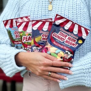 person holding 4 bags of stewart's candy. 