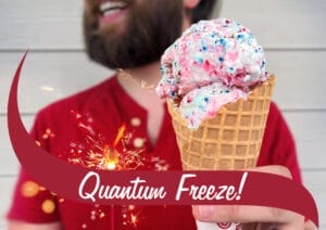Picture of man holding a waffle cone of Quantum Freeze ice cream and a sparkler. There's a maroon wave in front that reads "Quantum Freeze!".