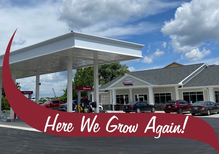 Image of our newly rebuilt Glenmont shop and gas pumps with a maroon wave in front that says "Here we grow again".
