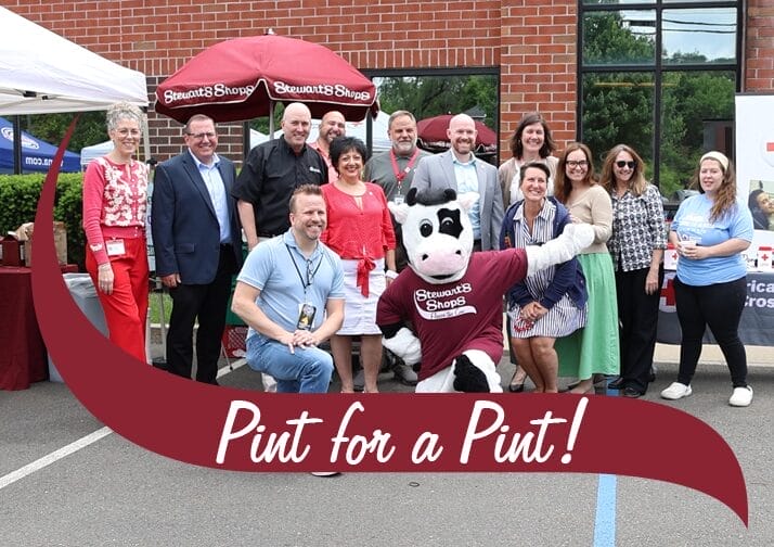 Picture taken outside of American Red Cross Building. 12 people in photo and Stewart's mascot, Flavor the Cow in front.