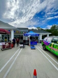 Image of radio tent and car next to ice cream cart in front of shop. 