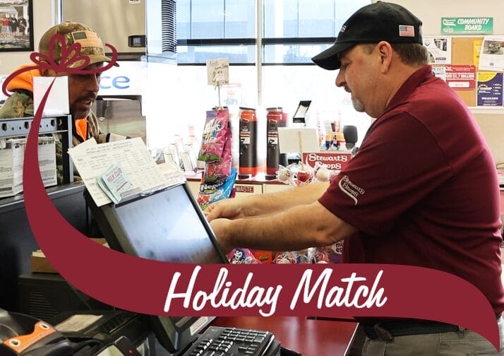 A store employee in a maroon uniform and black cap is assisting a customer at the checkout counter. The customer, wearing a camouflage jacket and a baseball cap, is engaged in conversation with the employee. The counter is filled with receipts, a cash register, and various products, including snacks and beverages. A maroon banner with white text reading 'Holiday Match' overlays the bottom of the image, with a decorative bow graphic on the left side. Behind the counter, shelves are stocked with coffee and other convenience store items, with a bright window in the background.