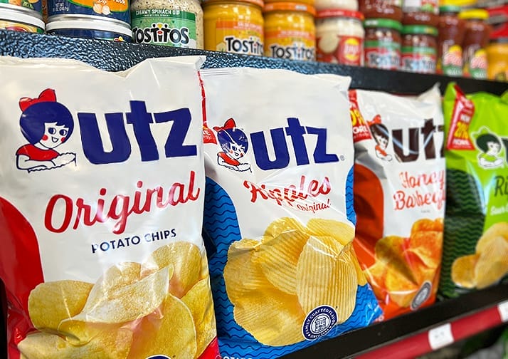 Image of a conveience store aisle of chips including original potato chips, ripple potato chips, sour cream and onion chips, and salt and vinegar chips.