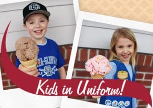 Two kids in uniforms holding up Stewart's ice cream cones.